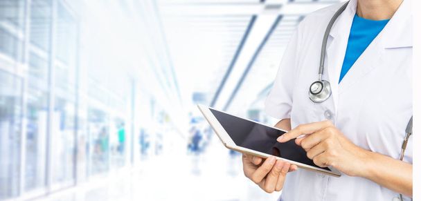 Double exposure of Doctor holding tablet with stethoscope on blurred hospital background. - Photo, Image