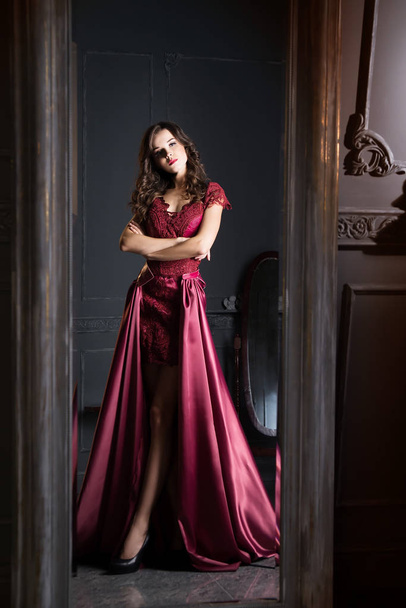 ワインレッドのサテンのドレスの若いブルネットの女性のミラー反射 - 写真・画像