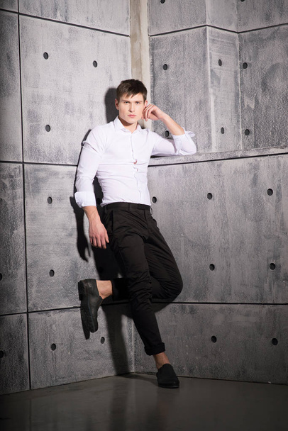 Stylish young man in white shirt posing on concrete background  - Фото, изображение