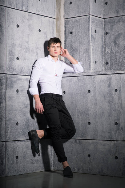 stylischer junger Mann im weißen Hemd posiert auf Betongrund  - Foto, Bild