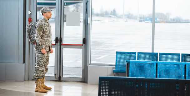 veteran in military uniform standing with backpack in departure lounge - Fotó, kép