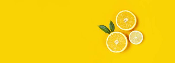 Ripe juicy lemons, orange and green leaves on bright yellow background. Lemon fruit, citrus minimal concept, vitamin C. Creative summer minimalistic background. Flat lay, top view, copy space - Fotó, kép