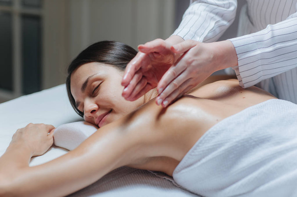 Young woman enjoying a back massage in a spa center. - Фото, изображение