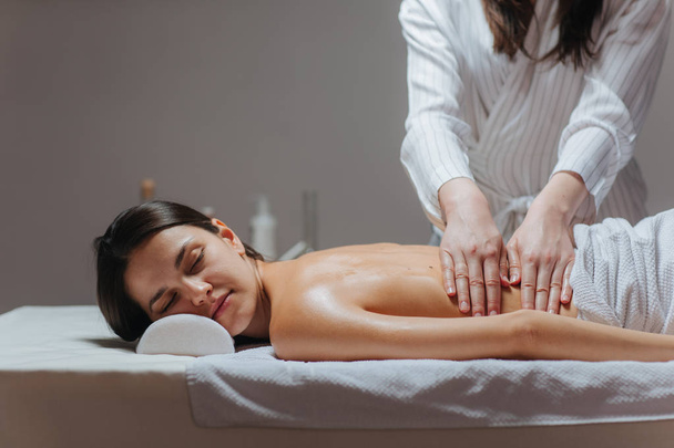 Young woman enjoying a back massage in a spa center. - Zdjęcie, obraz