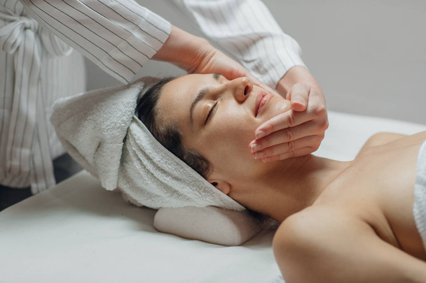 Mujer joven disfrutando de un masaje facial en un centro de spa
. - Foto, imagen