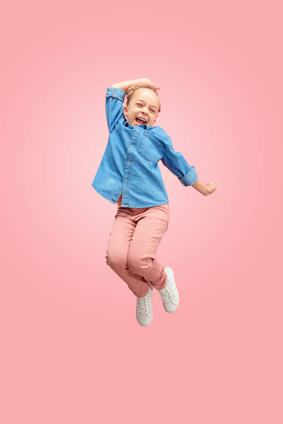 Young happy caucasian teen girl jumping in the air, isolated on pink studio background. - Fotografie, Obrázek