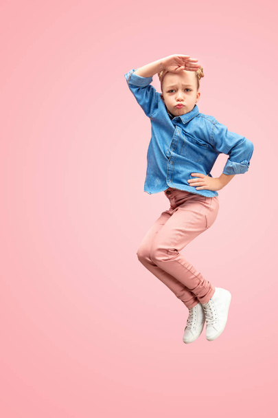 Young happy caucasian teen girl jumping in the air, isolated on pink studio background. - 写真・画像