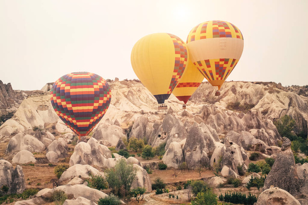 Beautiful hot air balloons flying over beautiful Goreme landscape at gold sunrise. Cappadocia is famous travel destination with limestone mountains, Turkey - Foto, Bild