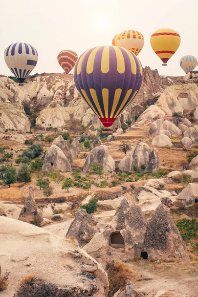 Όμορφη θερμού αέρα μπαλόνια πετώντας πάνω από το όμορφο τοπίο του Goreme χρυσό ξημέρωμα. Καππαδοκίας είναι διάσημος ταξιδιωτικός προορισμός με ασβεστολιθικά βουνά, Τουρκία - Φωτογραφία, εικόνα