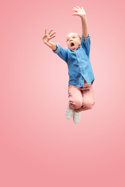 Young scared caucasian teen girl jumping in the air, isolated on pink studio background. - Fotografie, Obrázek