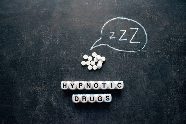 Białe tabletki Z kształtów i tekstu. Snu hipnotycznego narkotyków, uspokajające, pigułki, melatonina na tle ciemnej nocy - Zdjęcie, obraz