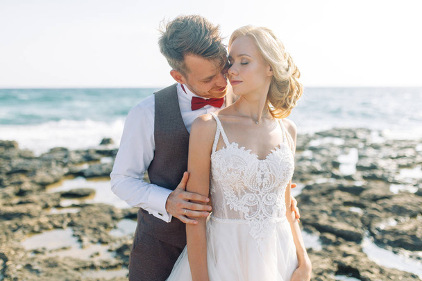 Wedding photo shoot on the beach. Couple at sunset walks and hugs, laughs and kisses. - Fotoğraf, Görsel