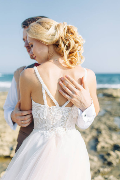 Wedding photo shoot on the beach. Couple at sunset walks and hugs, laughs and kisses. - Foto, Imagem