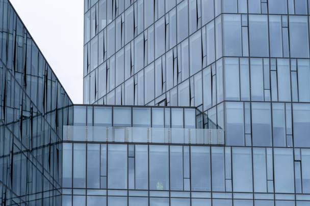 Фото современных небоскребов с большими окнами в деловом районе на фоне голубого неба
 - Фото, изображение