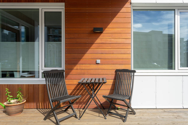 Foto de cerca de la terraza vacía con silla de madera muebles y mesa en casa moderna
 - Foto, imagen