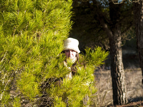  Frau mit weißem Hut posiert neben Baum - Foto, Bild