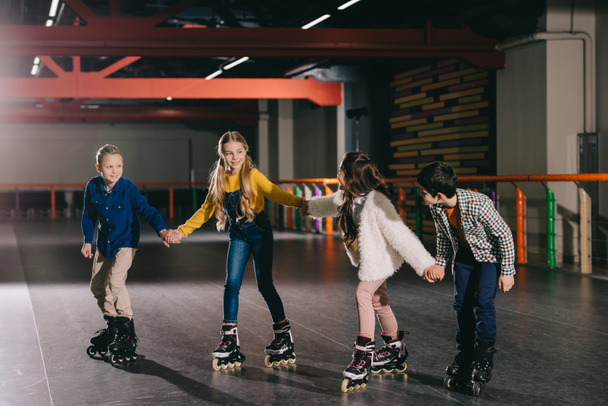 Smiling children in roller skating on roller rink and holding hands - Photo, Image
