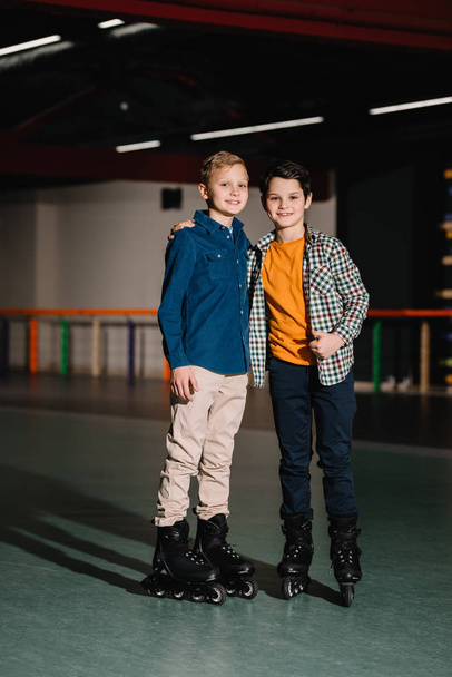 Selective focus of smiling boys in roller skates with one hugging friend - Fotoğraf, Görsel
