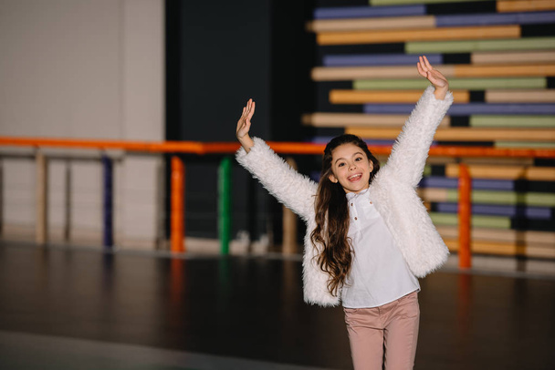 Selective focus of smiling child standing in roller rink with hands up - Foto, imagen