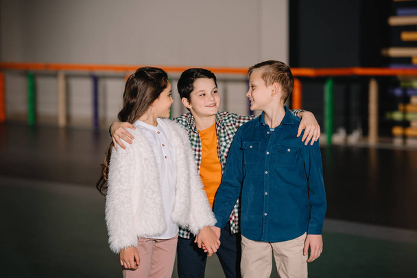Pretty boy hugging two smiling friends with holding hands  - Фото, изображение