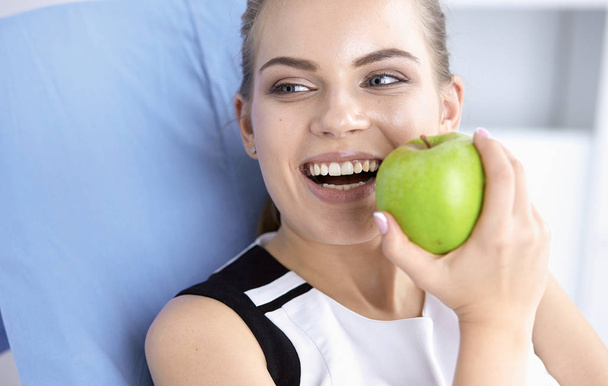 Όμορφη χαμογελαστή κοπέλα με ένα πράσινο μήλο στα χέρια - Φωτογραφία, εικόνα