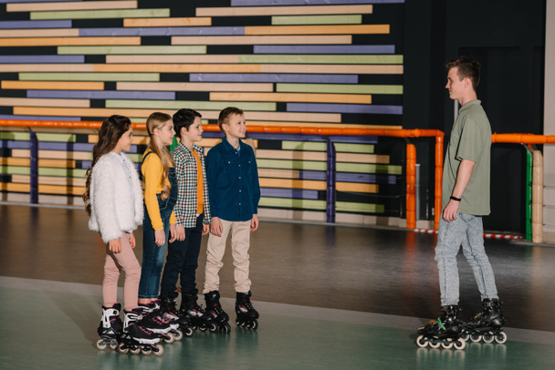 Smiling children in roller skates listening to trainers instructions - Valokuva, kuva