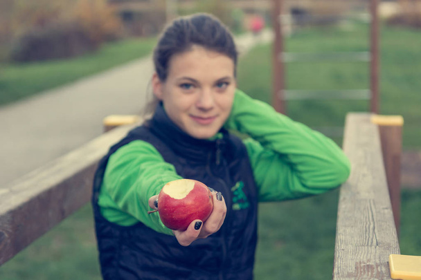 fitnes Trainer bietet im Outdoor-Fitnessstudio einen Apfel an. - Foto, Bild