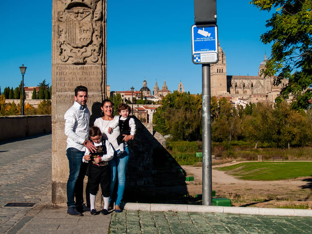 On Roma Köprüsü Salamanca, geleneksel giysiler ve Salamanca cathedral giymiş bir aile ile iki çocuk kardeş seyahat kucakladı - Fotoğraf, Görsel