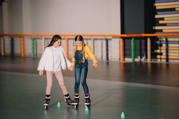 Beautiful kids practicing rolling skating while holding hands - 写真・画像