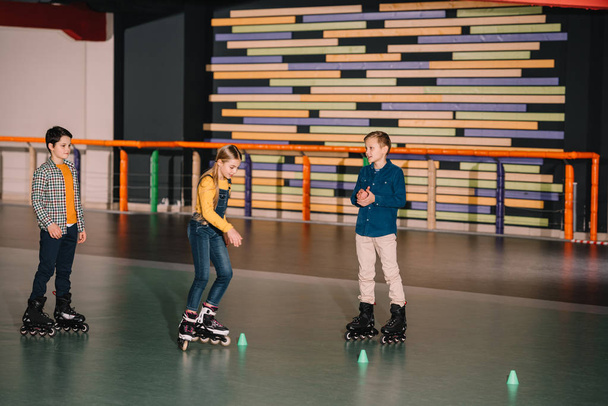 Pré-ados patineurs à roulettes pratiquant le patinage sur la patinoire ensemble
 - Photo, image