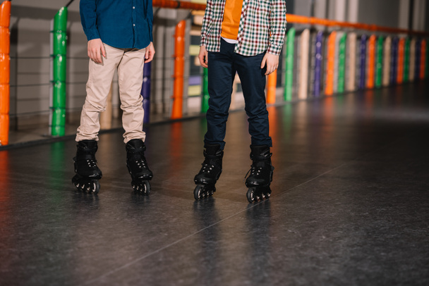 Partial view of boys in black roller skates posing on rink - Zdjęcie, obraz