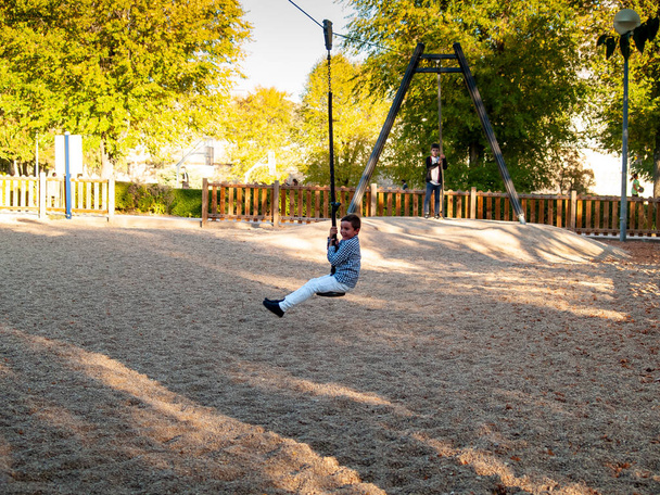  schattig jongen op swing op speeltuin - Foto, afbeelding