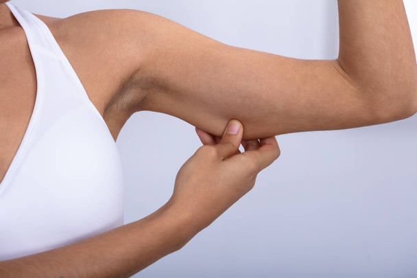 Close-up Of A Fit Young Woman Checking Excessive Fat On Her Arms Over White Background - Valokuva, kuva
