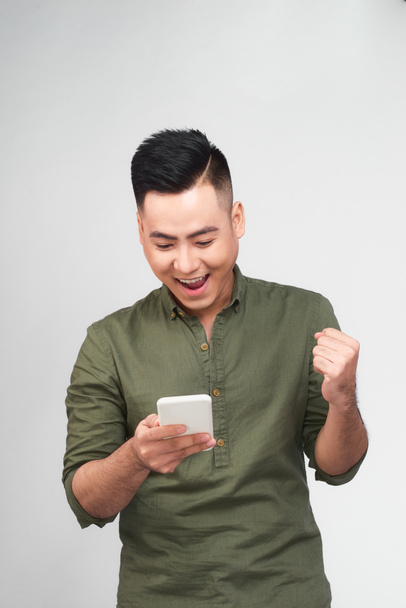 Homem feliz segurando smartphone e celebrando seu sucesso sobre fundo cinza
 - Foto, Imagem