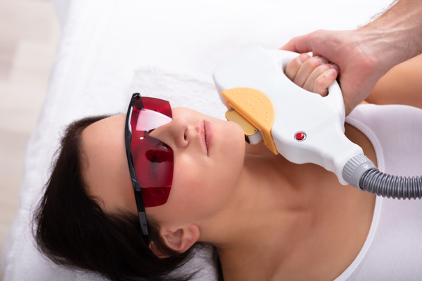 Gros plan sur la main d'esthéticienne qui donne un traitement de dépilation au laser à une jeune femme
 - Photo, image