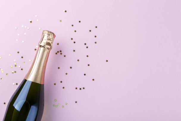 Flat lay of composition Champagne bottle and confetti on pink background copy space - Photo, Image