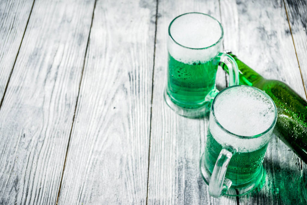 St. Patrick's day concept, two glasses and bottle with cold fresh cold green beer on wooden table, bar counter Background for St. Patrick's day and Oktoberfest menu. Copy space - Fotoğraf, Görsel