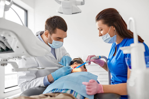 dentist treating kid teeth at dental clinic - Zdjęcie, obraz
