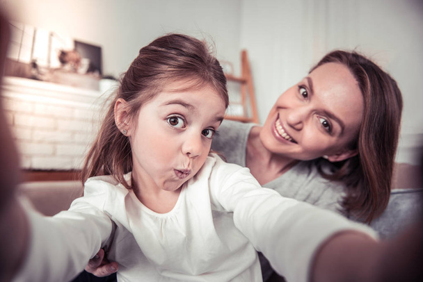 Positive cute girl taking photos with her mom - Foto, Bild