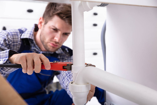 Young Male Plumber Repairing Sink Pipe With Adjustable Wrench - Φωτογραφία, εικόνα