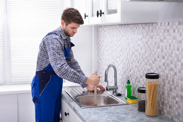 Μερική άποψη του αρσενικό υδραυλικός χρησιμοποιώντας έμβολο στο νεροχύτη της κουζίνας - Φωτογραφία, εικόνα