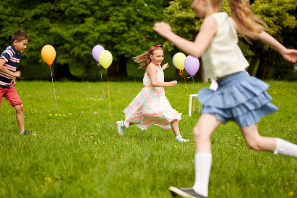 happy kids playing tag game at birthday party - Foto, Imagen