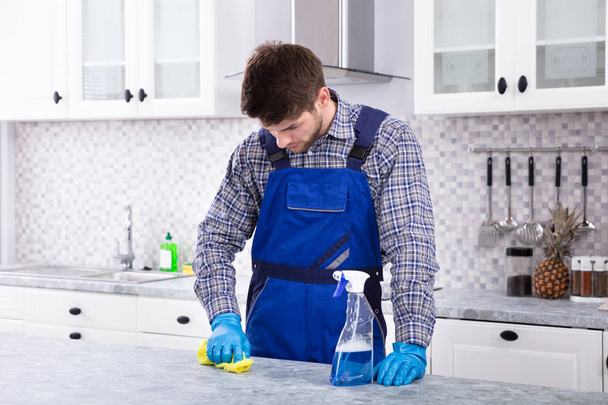 Close-up van een jonge Man reinigen vuil aanrecht met servet - Foto, afbeelding