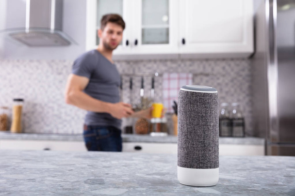 Close-up Of Wireless Speaker In Front Of Man Cutting Vegetables In Kitchen - Photo, image