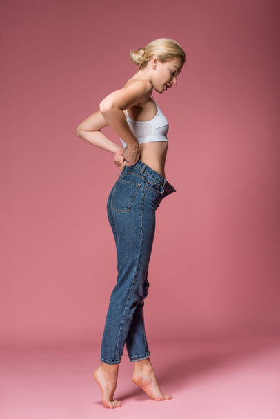 beautiful slim woman posing in jeans, on pink - Photo, Image