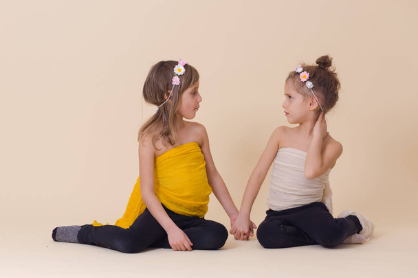 Duas meninas em roupas amarelas e brancas posando juntas
 - Foto, Imagem