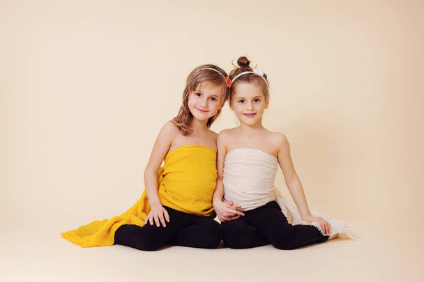 Két lány pózol együtt fantasy sárga és fehér ruhák - Fotó, kép