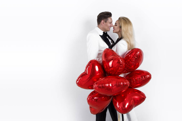Joyeux beau couple posant sur fond blanc et tenant des ballons coeur. Saint-Valentin. - Image
 - Photo, image