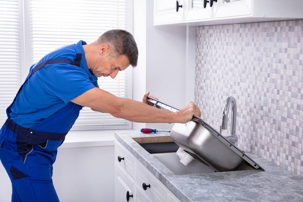 Photo Of Mature Male Workman Fixing Kitchen Sink - Φωτογραφία, εικόνα