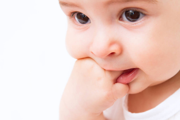 Mooie baby portret met hand in mond op witte achtergrond - Foto, afbeelding